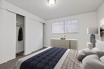 A white bedroom with a large bed and a closet
